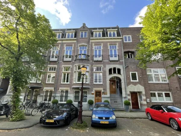 Voorgevel van een statig herenhuis aan de Oranje Nassaulaan met geparkeerde auto’s en bomen langs de straat.